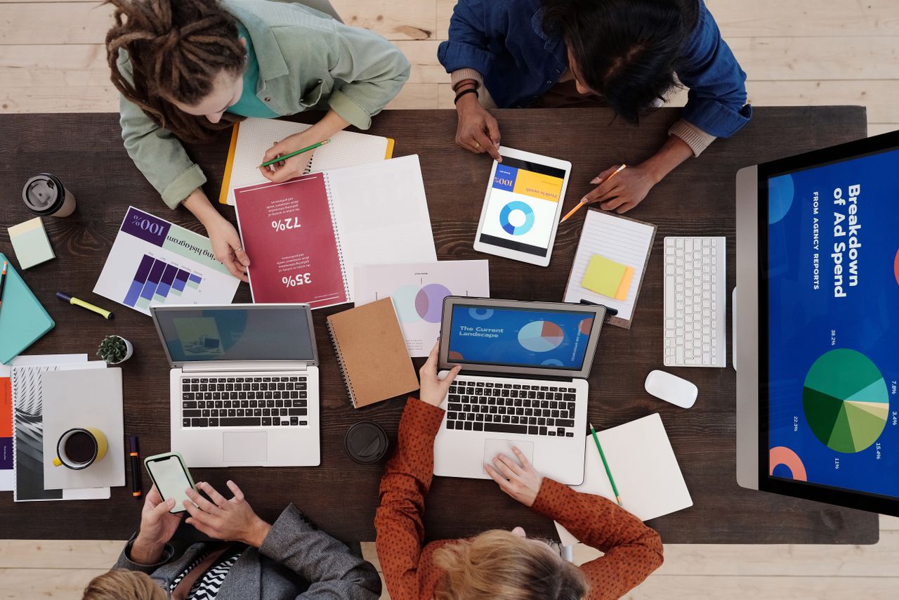 Une équipe variée travaille ensemble sur des stratégies de marketing digital autour d'une table, utilisant ordinateurs portables et tablettes.